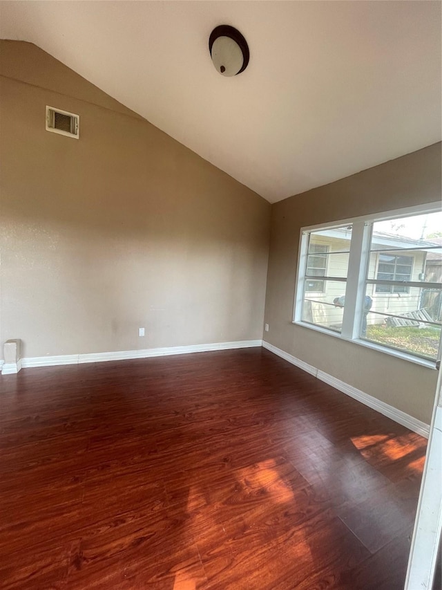 empty room with dark hardwood / wood-style flooring and vaulted ceiling