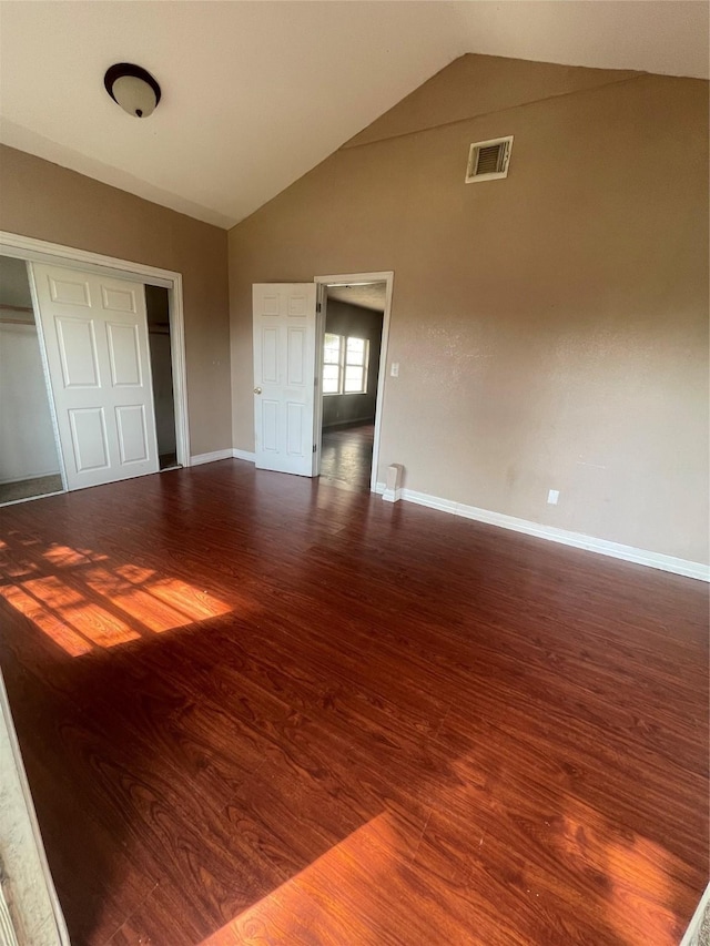 unfurnished bedroom featuring a closet, dark hardwood / wood-style flooring, and vaulted ceiling