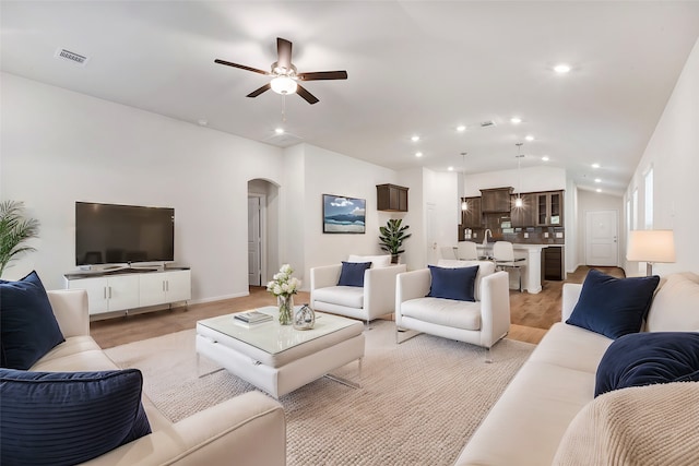 living room featuring ceiling fan, lofted ceiling, and light wood-type flooring