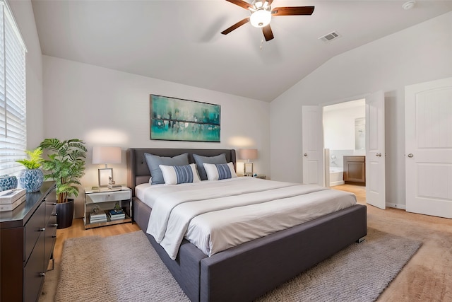 bedroom with ceiling fan, light wood-type flooring, ensuite bath, and vaulted ceiling