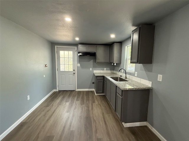 kitchen with sink, light stone countertops, gray cabinetry, and dark hardwood / wood-style flooring