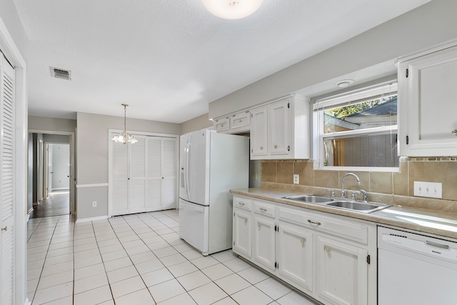 kitchen featuring backsplash, white cabinets, decorative light fixtures, and white appliances