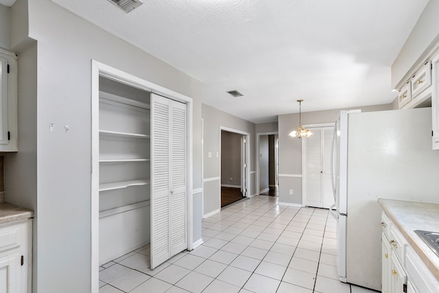 kitchen featuring white cabinets, a notable chandelier, pendant lighting, and light tile patterned floors