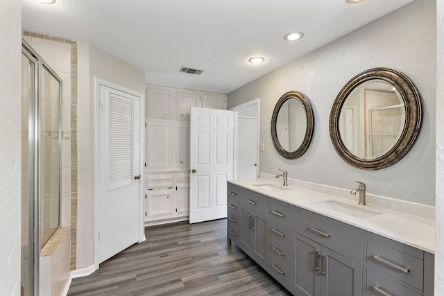 bathroom featuring vanity, a textured ceiling, a shower with shower door, and wood-type flooring