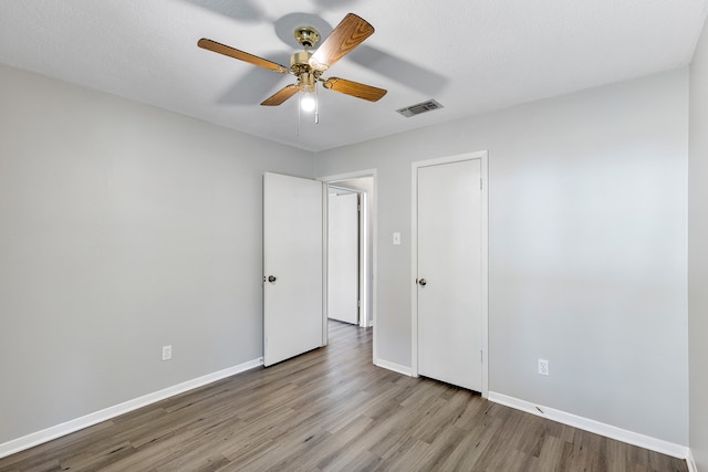 unfurnished bedroom with light hardwood / wood-style flooring, a textured ceiling, and ceiling fan