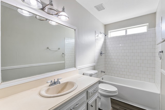 full bathroom featuring vanity, hardwood / wood-style floors, tiled shower / bath combo, and toilet