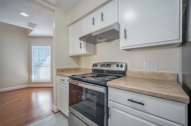 kitchen with stainless steel range with electric stovetop, white cabinetry, a textured ceiling, and light wood-type flooring