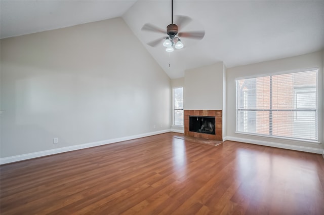 unfurnished living room with high vaulted ceiling, wood-type flooring, a tile fireplace, and ceiling fan