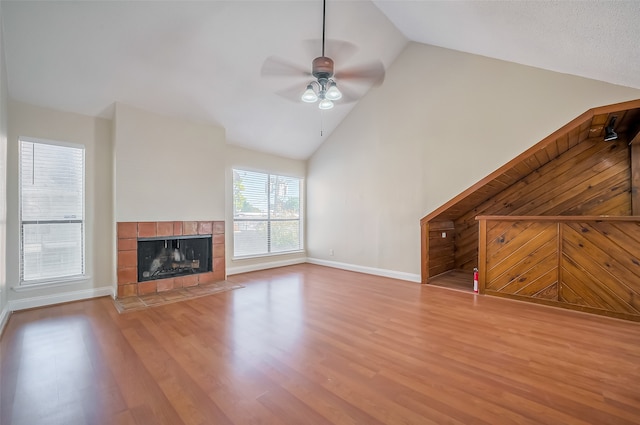 unfurnished living room with light hardwood / wood-style flooring, a fireplace, high vaulted ceiling, and ceiling fan