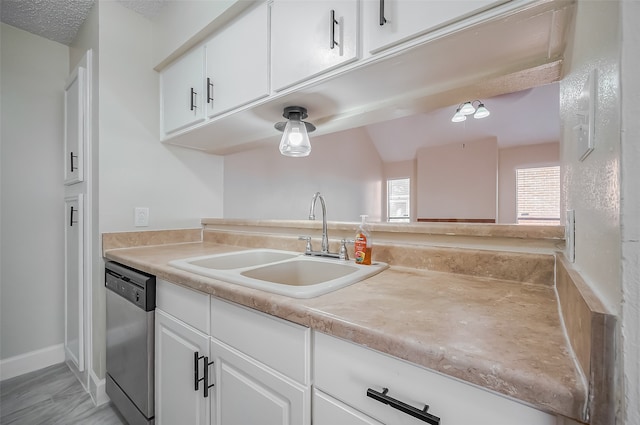 kitchen with white cabinets, stainless steel dishwasher, sink, and a textured ceiling