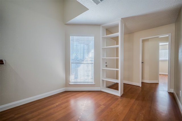 unfurnished room featuring a textured ceiling and hardwood / wood-style floors