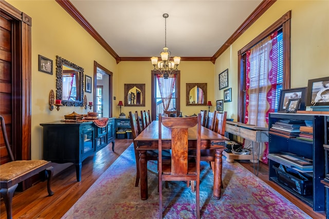 dining room with an inviting chandelier, crown molding, and wood finished floors