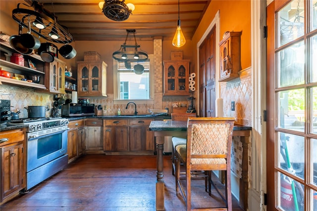 kitchen featuring brown cabinets, dark countertops, dark wood-style floors, and stainless steel gas stove