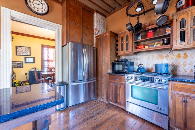 kitchen with dark stone countertops, stainless steel appliances, backsplash, and dark hardwood / wood-style flooring