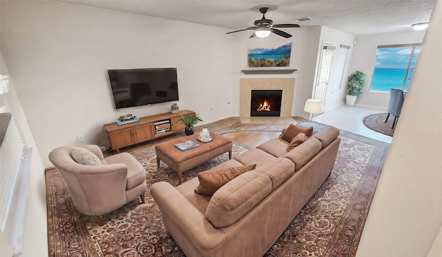 living room featuring a tiled fireplace, hardwood / wood-style flooring, and ceiling fan