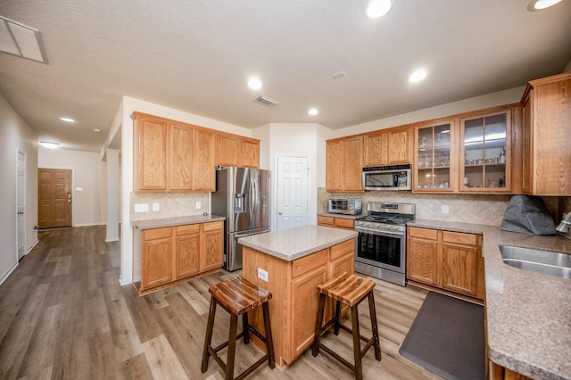 4609 Buescher Ct, Pearland, TX 77584 - kitchen with a sink, visible vents, stainless steel appliances, a center island, and light wood-type flooring