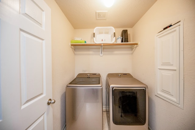 laundry room with washing machine and clothes dryer and a textured ceiling