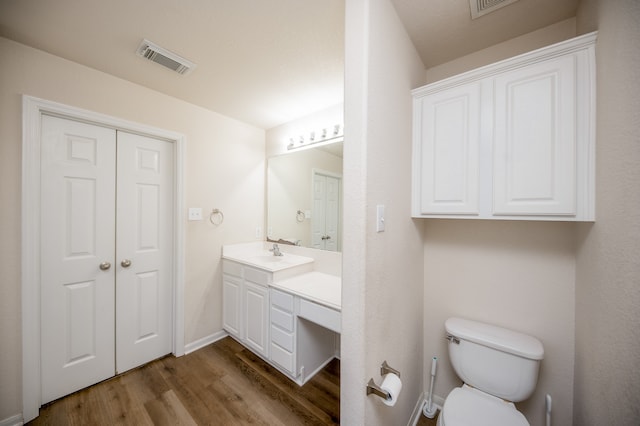 bathroom with vanity, toilet, and wood-type flooring