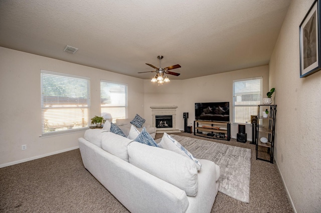 4609 Buescher Ct, Pearland, TX 77584 - carpeted living area featuring ceiling fan, a fireplace with raised hearth, baseboards, visible vents, and a textured ceiling