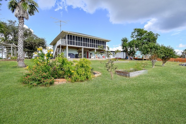 back of house featuring a lawn and a sunroom