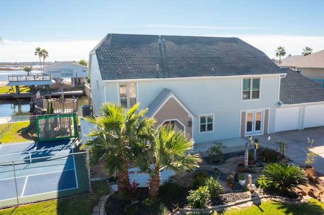 back of house with cooling unit, a garage, and a water view