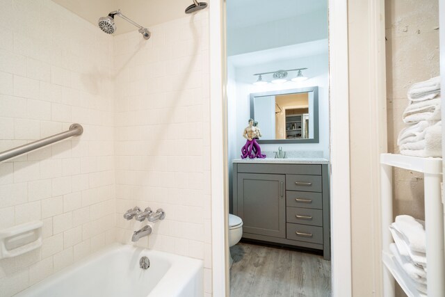 full bathroom with vanity, toilet, tiled shower / bath, and hardwood / wood-style floors