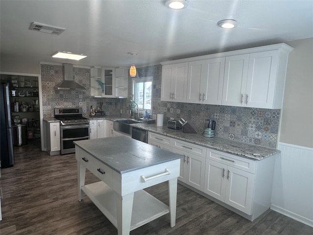 kitchen with wall chimney range hood, black appliances, white cabinetry, and decorative light fixtures