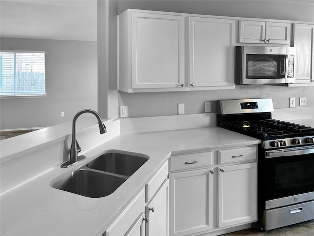 kitchen with appliances with stainless steel finishes, white cabinetry, and sink