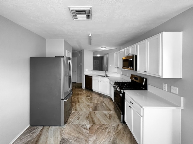 kitchen with a textured ceiling, appliances with stainless steel finishes, sink, and white cabinets