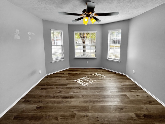 unfurnished room featuring a textured ceiling, ceiling fan, a wealth of natural light, and dark hardwood / wood-style flooring