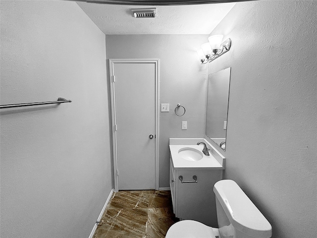 bathroom with vanity, a textured ceiling, and toilet