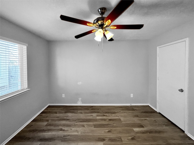 empty room with ceiling fan and dark hardwood / wood-style flooring