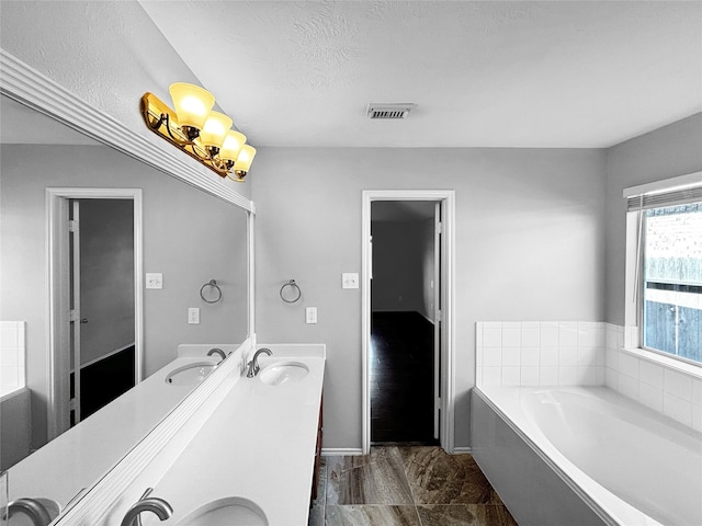 bathroom featuring vanity, a textured ceiling, and a bath