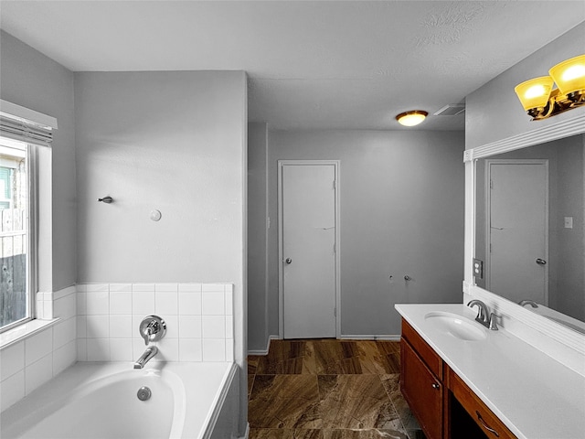 bathroom featuring vanity, a tub to relax in, and a textured ceiling