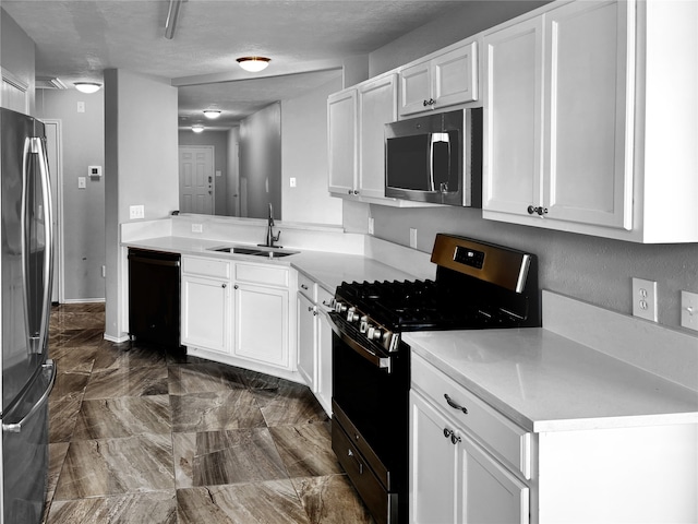 kitchen with a textured ceiling, appliances with stainless steel finishes, sink, and white cabinets