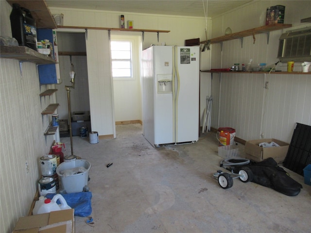 garage featuring a wall mounted air conditioner and white refrigerator with ice dispenser