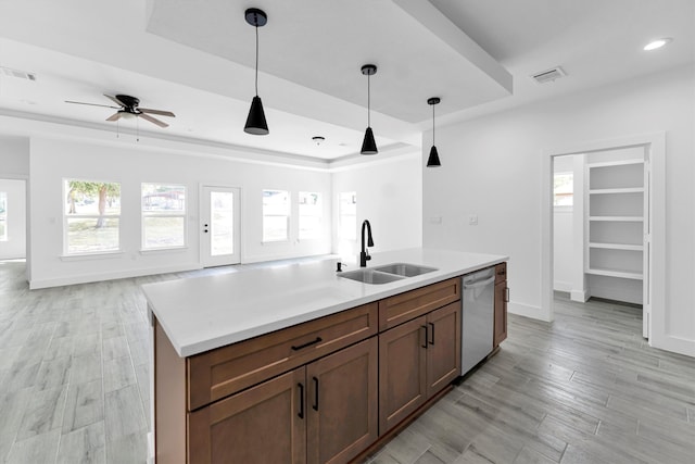 kitchen with sink, hanging light fixtures, a kitchen island with sink, light wood-type flooring, and dishwasher