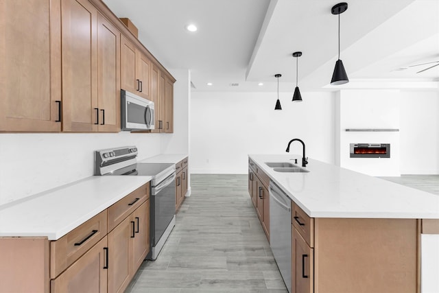 kitchen featuring light hardwood / wood-style floors, sink, appliances with stainless steel finishes, an island with sink, and pendant lighting