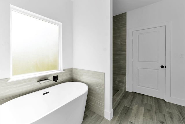 bathroom featuring hardwood / wood-style flooring, a bathing tub, and tile walls