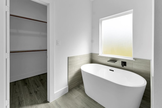 bathroom with tile walls, a bath, and hardwood / wood-style flooring