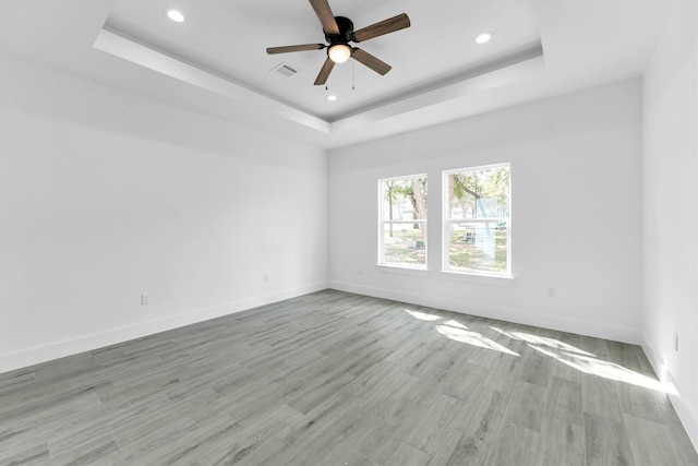 unfurnished room featuring ceiling fan, light hardwood / wood-style floors, and a raised ceiling