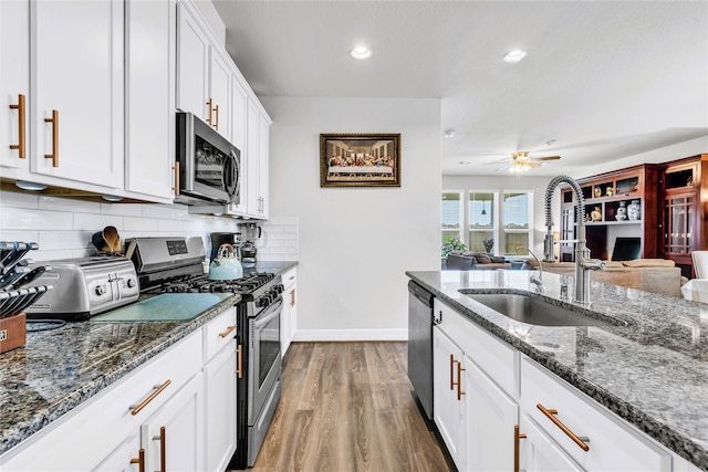 kitchen with hardwood / wood-style floors, white cabinets, appliances with stainless steel finishes, tasteful backsplash, and sink