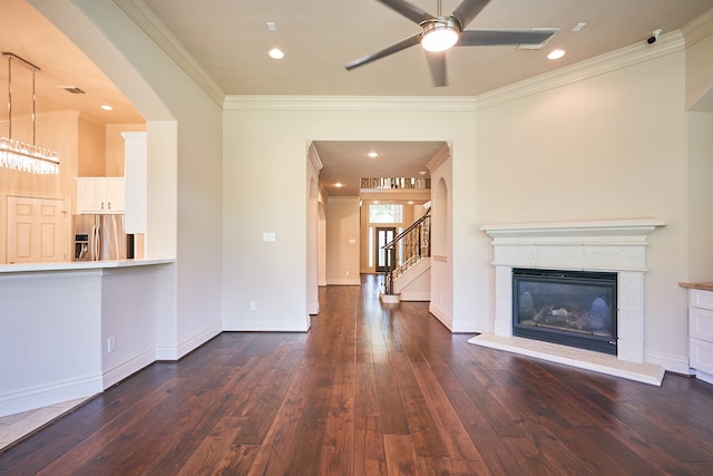 unfurnished living room featuring ceiling fan, dark hardwood / wood-style floors, ornamental molding, and a fireplace