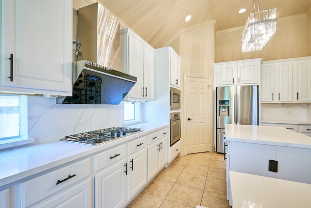 kitchen featuring appliances with stainless steel finishes, hanging light fixtures, white cabinetry, wall chimney exhaust hood, and an inviting chandelier