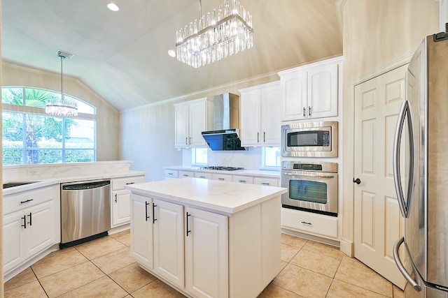 kitchen with wall chimney exhaust hood, a center island, pendant lighting, an inviting chandelier, and appliances with stainless steel finishes