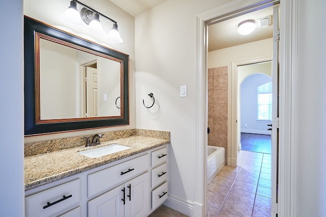 bathroom with vanity, tile patterned floors, and a washtub