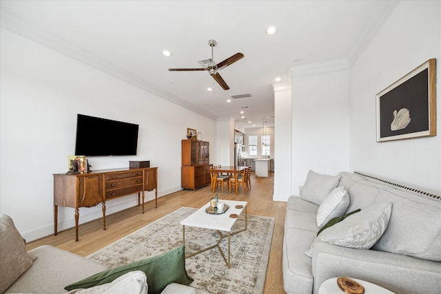 living room with light hardwood / wood-style flooring, ornamental molding, and ceiling fan