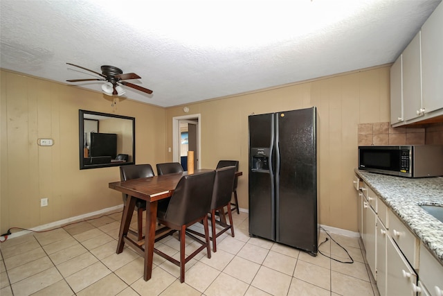 tiled dining room with a textured ceiling, ornamental molding, wooden walls, and ceiling fan