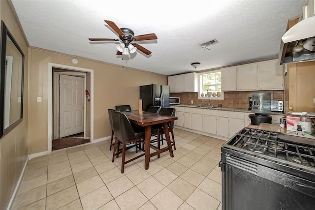 kitchen featuring ventilation hood, black appliances, sink, white cabinetry, and tasteful backsplash