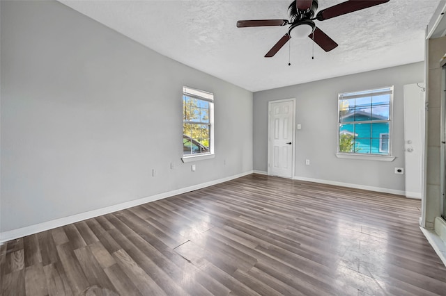 empty room with a textured ceiling, dark wood-type flooring, and ceiling fan